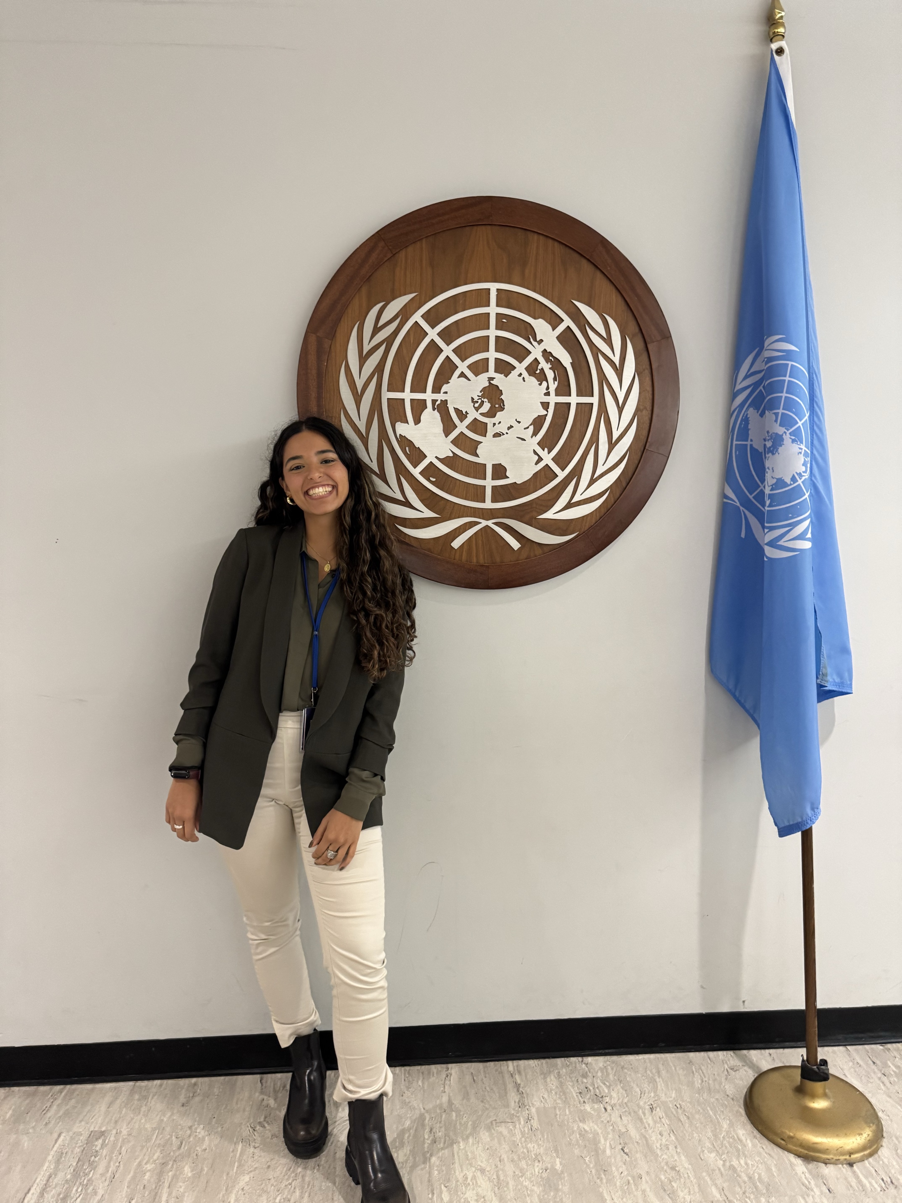 Zoe junto al emblema y la bandera de las Naciones Unidas