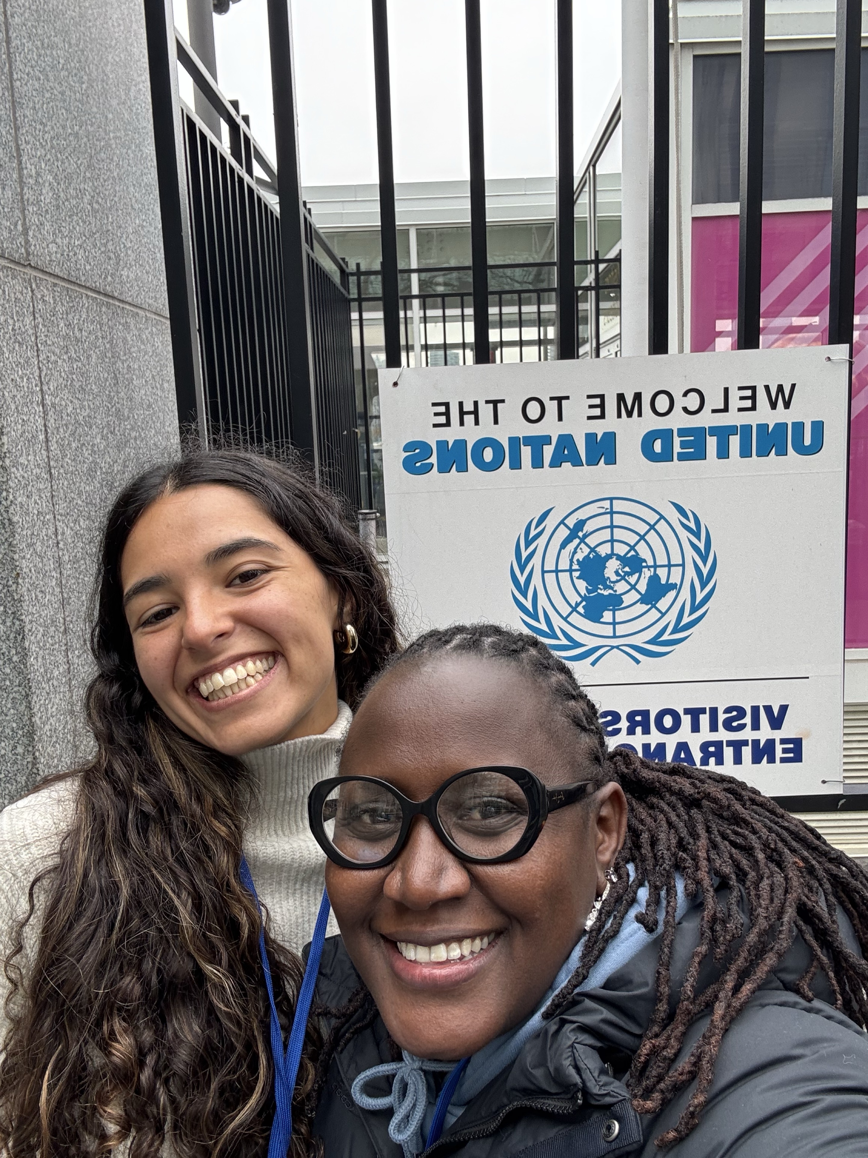 Zoe junto a otra participante frente a la entrada de Naciones Unidas