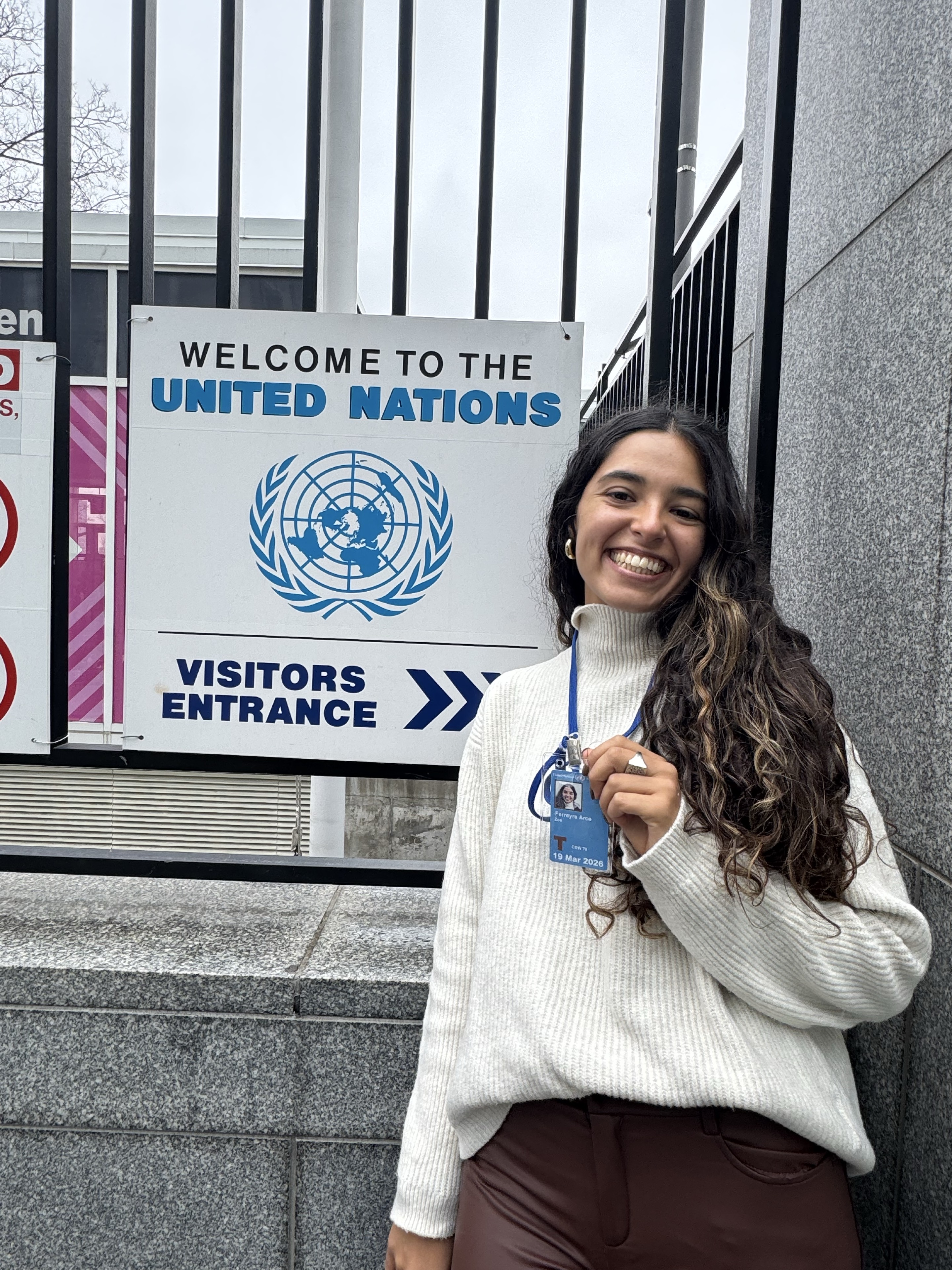 Zoe sonriendo junto a la entrada de visitantes de Naciones Unidas